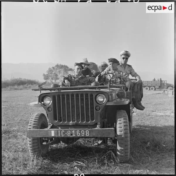 Une jeep chargée de soldats traverse un pré