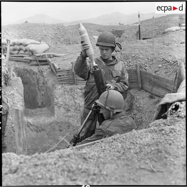 Un soldat brandit un obus dans une tranchée