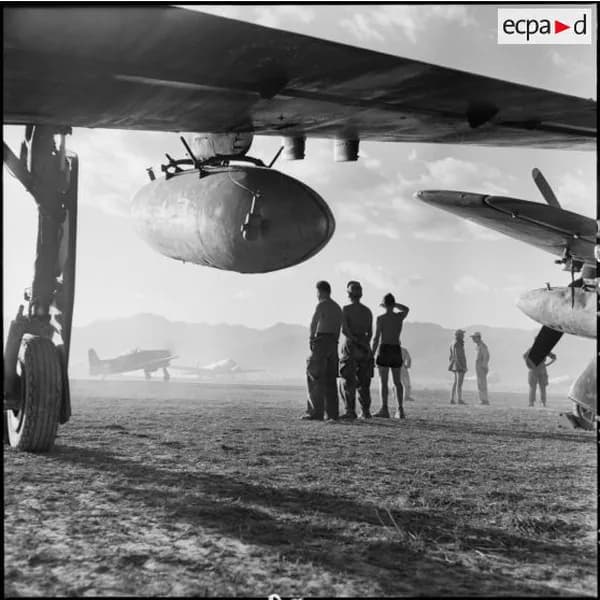 Des soldats sous l'aile d'un avion, sur la piste