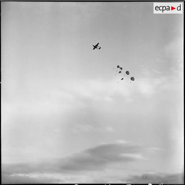 Un avion et des parachutes dans un ciel voilé